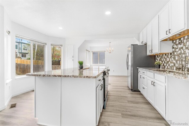 524 Rider Ridge Dr, Longmont, CO 80504 - kitchen featuring baseboards, light wood finished floors, an inviting chandelier, a sink, and a kitchen island