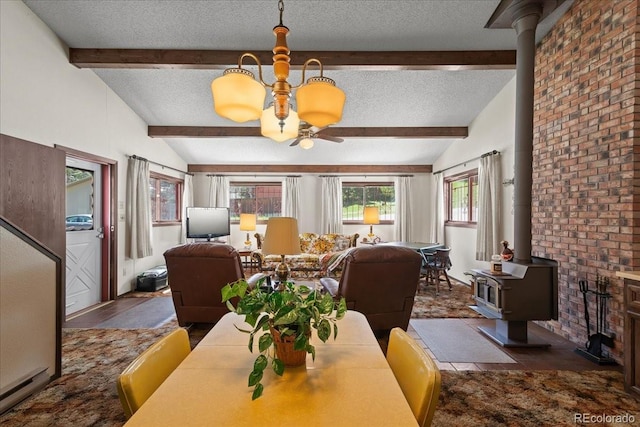 dining room with a textured ceiling, lofted ceiling with beams, and a wood stove