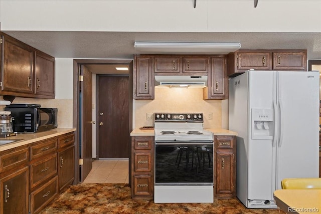 kitchen with tile flooring, a textured ceiling, and white appliances