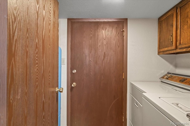 washroom with washer and dryer, cabinets, and a textured ceiling