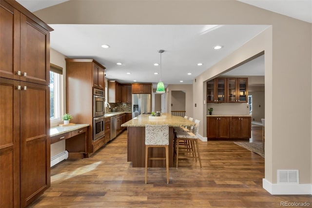 kitchen with stainless steel fridge with ice dispenser, a kitchen island, a baseboard radiator, and hardwood / wood-style flooring