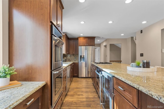 kitchen with light stone countertops, tasteful backsplash, wine cooler, light hardwood / wood-style floors, and appliances with stainless steel finishes