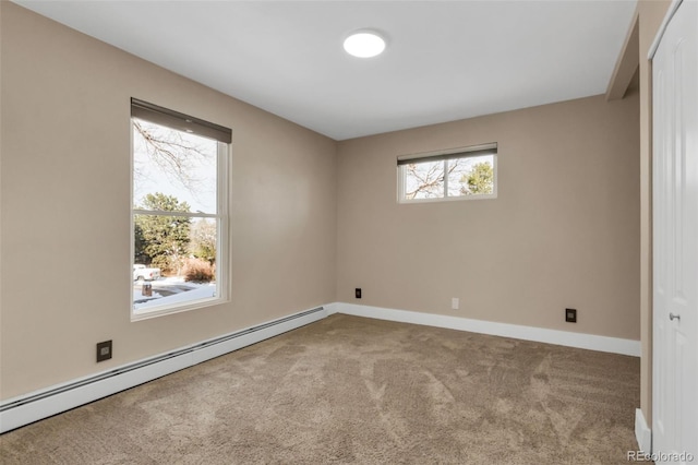 empty room with carpet flooring, a wealth of natural light, and a baseboard heating unit