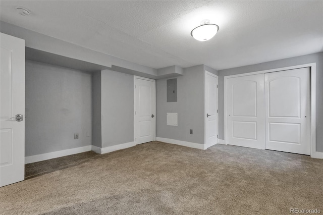 basement featuring a textured ceiling, carpet floors, and electric panel