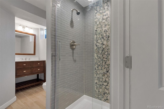 bathroom featuring toilet, hardwood / wood-style floors, vanity, and tiled shower