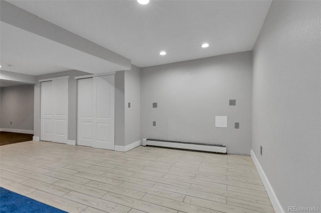 basement with light wood-type flooring and a baseboard heating unit