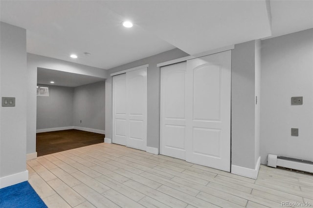 basement featuring light hardwood / wood-style floors and a baseboard heating unit