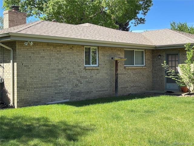 1602 S Lamar St, Lakewood, CO 80232 - view of side of property with roof with shingles, a lawn, brick siding, and a chimney