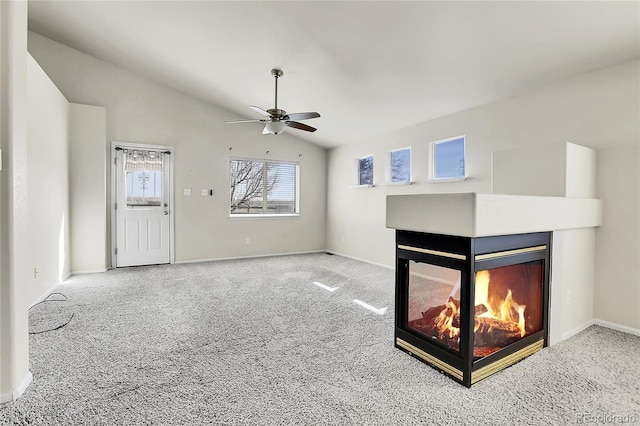 unfurnished living room with carpet, baseboards, a multi sided fireplace, ceiling fan, and vaulted ceiling