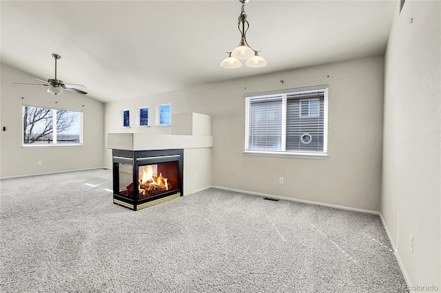 carpeted living room with a ceiling fan, visible vents, baseboards, a multi sided fireplace, and vaulted ceiling