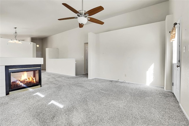 unfurnished living room with a multi sided fireplace, a ceiling fan, carpet, and vaulted ceiling