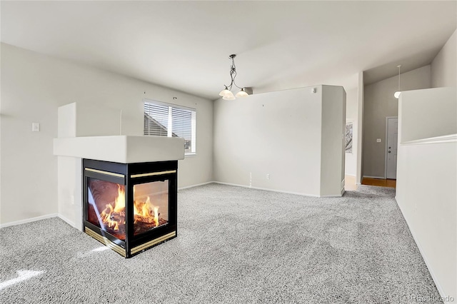 unfurnished living room with carpet, a multi sided fireplace, and baseboards