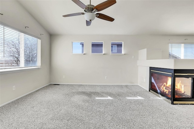 unfurnished living room with a multi sided fireplace, a ceiling fan, carpet, and baseboards