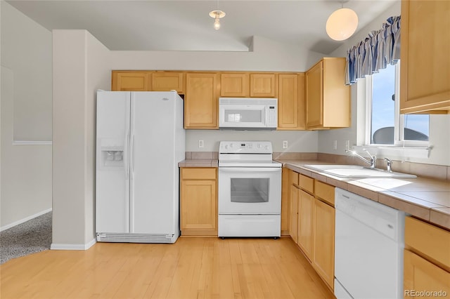 kitchen with light brown cabinets, white appliances, and a sink