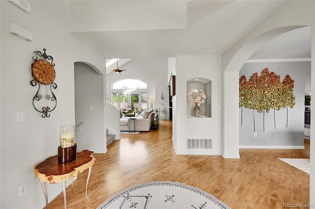 entrance foyer featuring arched walkways, baseboards, wood finished floors, and visible vents