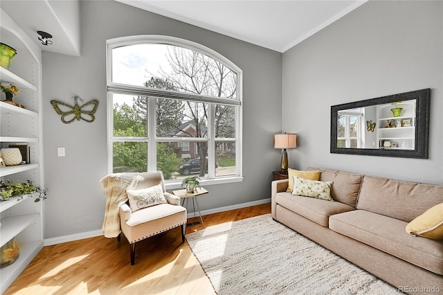 living area with baseboards, ornamental molding, wood finished floors, and a wealth of natural light