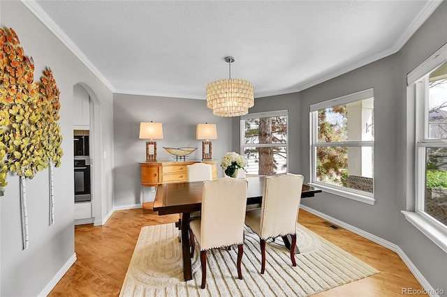 dining space with arched walkways, a notable chandelier, plenty of natural light, and ornamental molding