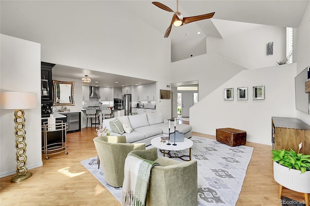 living area with ceiling fan, high vaulted ceiling, light wood-style flooring, recessed lighting, and baseboards