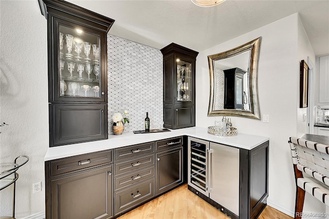 bar featuring light wood-type flooring, a sink, beverage cooler, and a dry bar