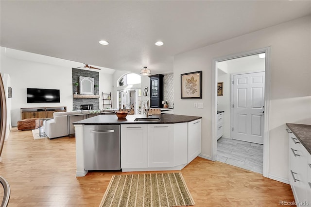 kitchen with a fireplace, light wood-style floors, white cabinetry, a sink, and dishwasher