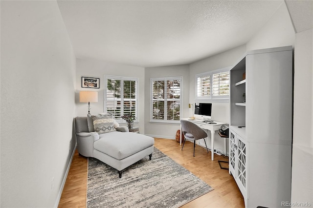 office area featuring a textured ceiling, baseboards, and light wood-style floors