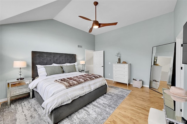 bedroom featuring a ceiling fan, visible vents, wood finished floors, high vaulted ceiling, and baseboards