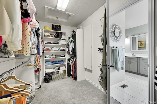 spacious closet featuring light colored carpet, a sink, and visible vents