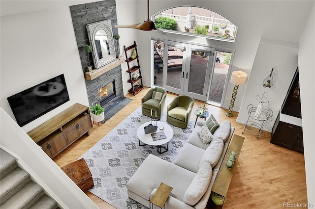 living room featuring a towering ceiling, french doors, wood finished floors, and a fireplace