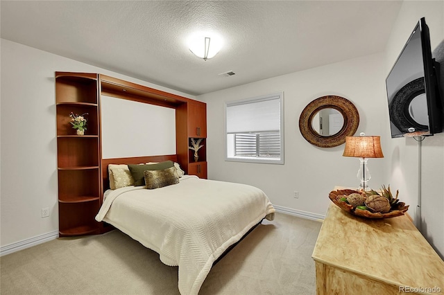 bedroom featuring a textured ceiling, baseboards, visible vents, and light carpet