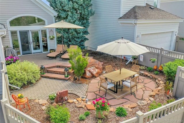 view of yard with fence, a deck, outdoor dining area, french doors, and an attached garage