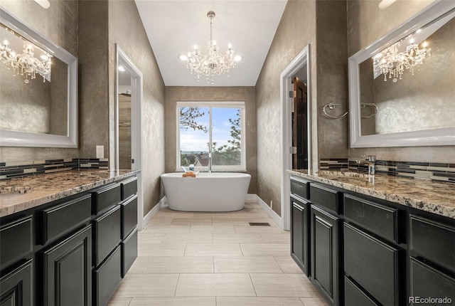 bathroom featuring a freestanding tub, two vanities, a sink, baseboards, and a chandelier