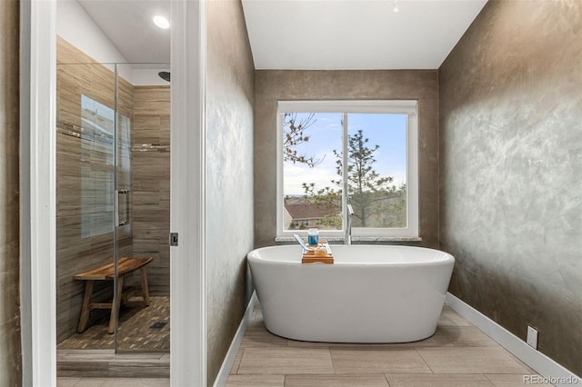 bathroom featuring baseboards, a freestanding bath, and a stall shower