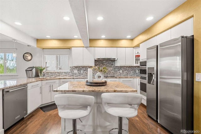 kitchen with dark wood-style flooring, stainless steel appliances, white cabinetry, and tasteful backsplash