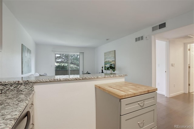 kitchen featuring baseboards, dark wood-style flooring, butcher block countertops, and visible vents