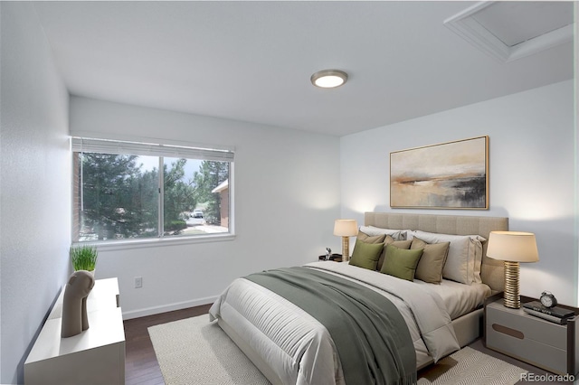 bedroom featuring dark wood-style flooring, attic access, and baseboards