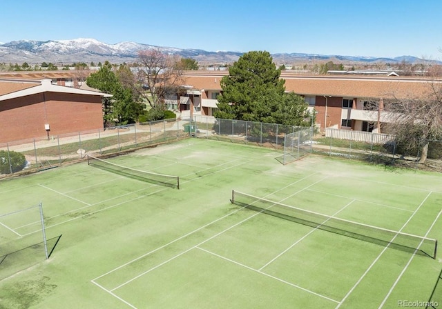 view of tennis court featuring a mountain view and fence