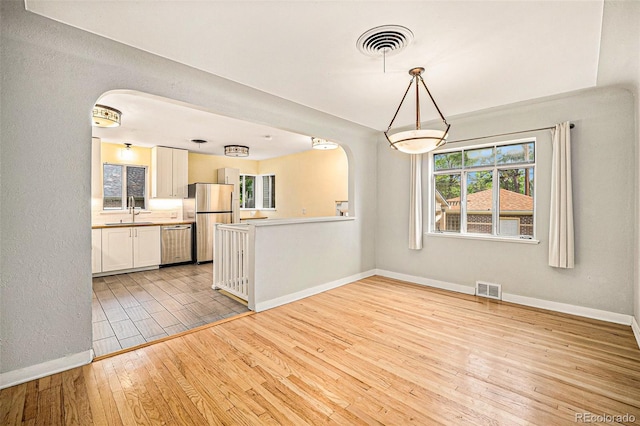 2526 W 39th Ave, Denver, CO 80211 - kitchen with stainless steel appliances, arched walkways, light wood-style floors, and baseboards