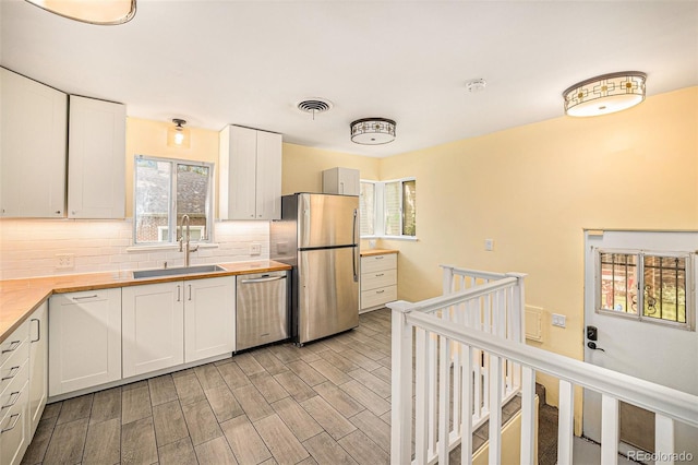 2526 W 39th Ave, Denver, CO 80211 - kitchen with appliances with stainless steel finishes, a sink, backsplash, and white cabinetry