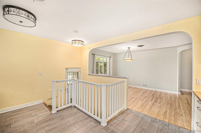 2526 W 39th Ave, Denver, CO 80211 - hallway with arched walkways, light wood-type flooring, an upstairs landing, and baseboards