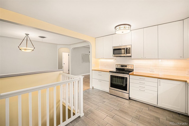 2526 W 39th Ave, Denver, CO 80211 - kitchen with appliances with stainless steel finishes, wood counters, decorative backsplash, and light wood-style flooring
