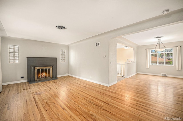 2526 W 39th Ave, Denver, CO 80211 - unfurnished living room featuring light wood-type flooring, arched walkways, a fireplace with flush hearth, and baseboards