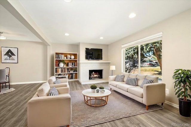 living area with recessed lighting, a fireplace, baseboards, and wood finished floors