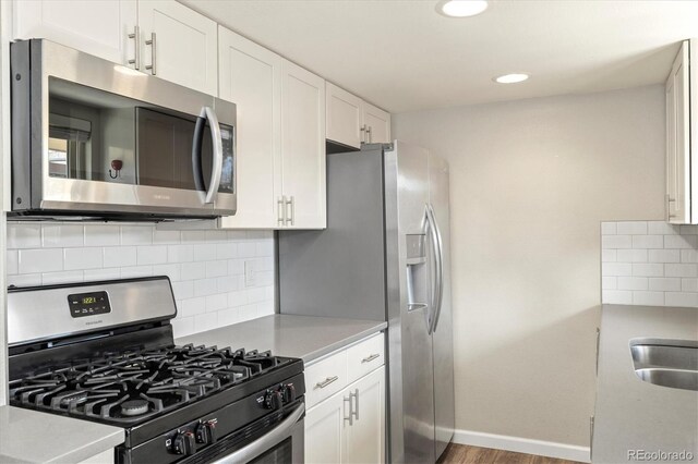 kitchen with baseboards, light countertops, white cabinets, appliances with stainless steel finishes, and tasteful backsplash