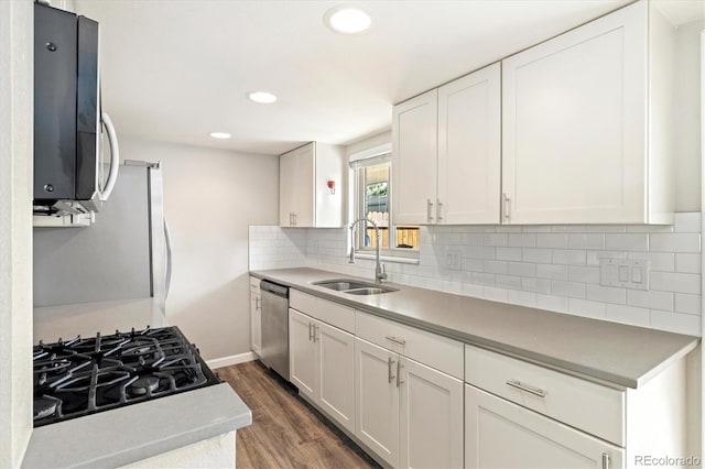 kitchen featuring dark wood-type flooring, a sink, white cabinetry, stainless steel appliances, and decorative backsplash