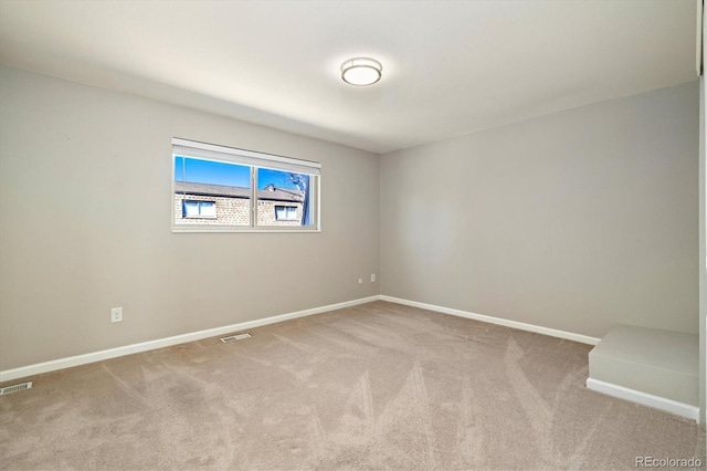 empty room with carpet flooring, visible vents, and baseboards