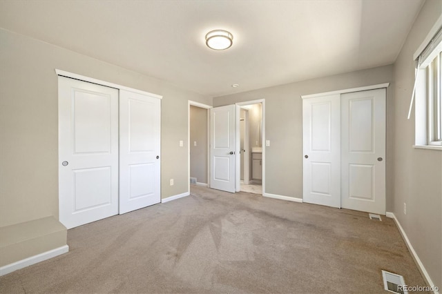 unfurnished bedroom featuring ensuite bathroom, baseboards, visible vents, and carpet floors