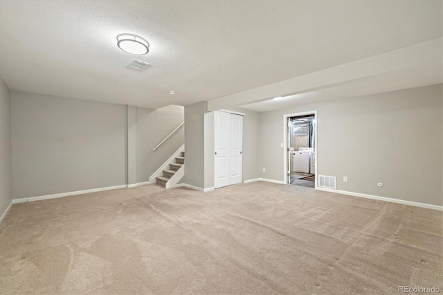 finished below grade area featuring washer and dryer, visible vents, baseboards, and stairs