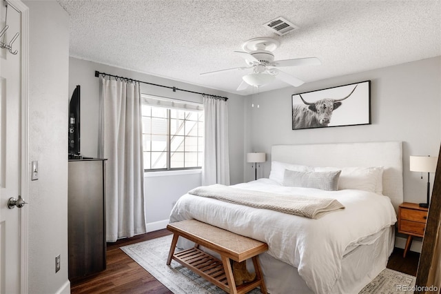 bedroom with ceiling fan, dark hardwood / wood-style floors, and a textured ceiling