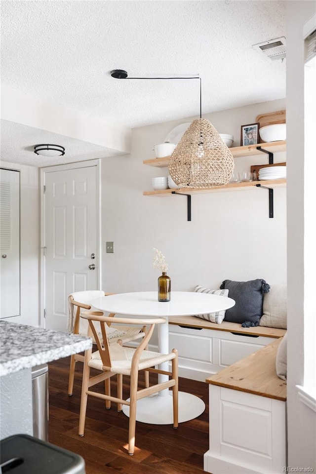 dining area featuring breakfast area, dark hardwood / wood-style flooring, and a textured ceiling