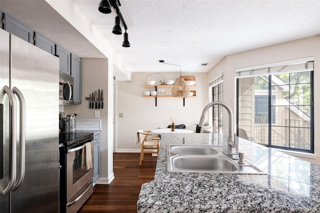 kitchen featuring gray cabinets, sink, stainless steel appliances, dark wood-type flooring, and a textured ceiling